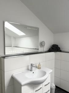 a white bathroom with a sink and a mirror at Neue Moderne FeWo Europa-Park & Rulantica in Ringsheim