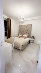 a white bedroom with a bed and a chandelier at Golden House in Dreux