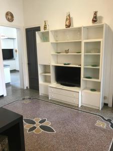 uma estante de livros brancos com uma televisão numa sala de estar em Appartamento davanti al mare em Savona