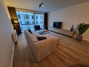 a living room with a couch and a tv at Luxueus, ruim appartement op 350m van het strand in Ostend