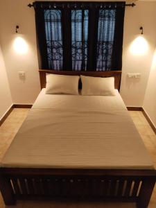 un grande letto in una stanza con due finestre di The Chill House a Cochin