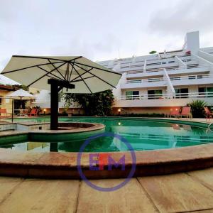 een zwembad met een parasol en een groot gebouw bij Flat Varandas Ponta Negra-EFM408 in Natal
