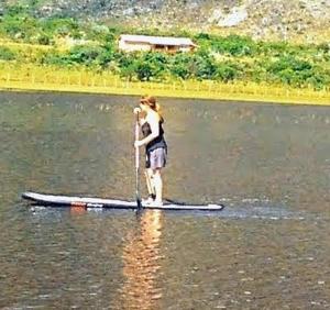 une femme debout sur une planche de paddle dans l'eau dans l'établissement Casa do Lago Lapinha da Serra, à Santana do Riacho