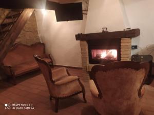sala de estar con chimenea y 2 sillas en Ca' Marcella terra cielo tre livelli con soppalco, en Montetiffi