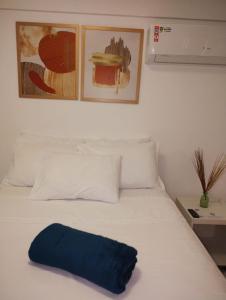uma cama branca com uma almofada azul em Studio FG hospedagem em Maceió
