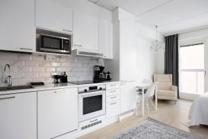 a white kitchen with white cabinets and a table at City Island Studio Apartment, 4 beds, free street parking with parking disc, bus stop 200m in Helsinki