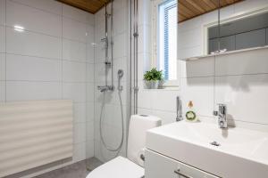 La salle de bains blanche est pourvue d'une douche et d'un lavabo. dans l'établissement City Island Studio Apartment, 4 beds, free street parking with parking disc, bus stop 200m, à Helsinki
