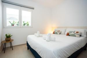 a large white bed in a room with two windows at Naim Playa in Cala del Moral
