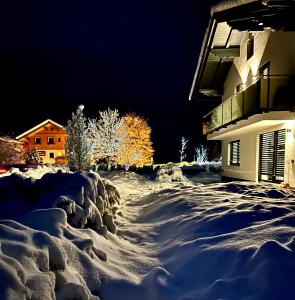 a snow covered driveway in front of a building at night at My Appartements in Untertauern