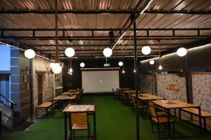 a room with tables and chairs and a projection screen at BACPAC MONKEY COLIVING in Visakhapatnam