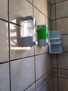 a green cup in a holder on a tiled wall at Santa Catarina Hostel in Florianópolis