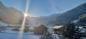 a snow covered village with the sun shining through the mountains at Ferienwohnung Marlin in Sankt Gallenkirch