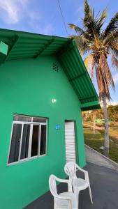 two white chairs sitting outside of a green house at ECO CHALÉ PARK CACHOEIRAS in Presidente Figueiredo