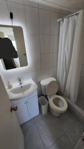 łazienka z toaletą, umywalką i lustrem w obiekcie Amplio Departamento Central Piso 11 Frente Casino Luckia w mieście Arica