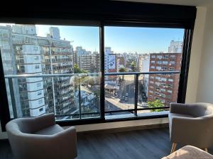 a room with two chairs and a large window at EUGE Apart in Montevideo