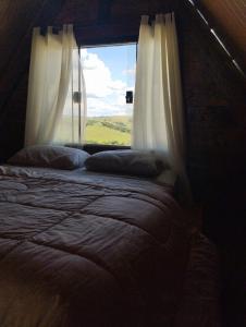 a bedroom with a window with a view of a field at Ecovalle São Thomé - Chalé do Sol in São Thomé das Letras +13 photos
