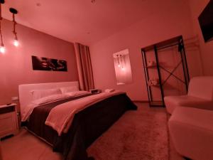 1 dormitorio con paredes rosas, 1 cama y 1 silla en Casa Auri, en Nápoles