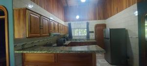 a kitchen with wooden cabinets and a black refrigerator at Casa Tabacón in Puerto Jiménez
