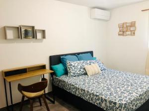 um quarto com uma cama com almofadas azuis e uma cadeira em Appartement neuf 4/6 personnes, près de la plage em Les Trois-Îlets