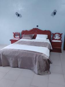a bedroom with a large bed with a wooden headboard at RESIDENCE DU PELERIN - Villa l'écrin de verdure à Bandjoun in Bandjoun
