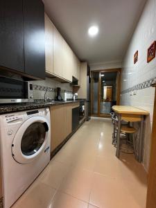 a kitchen with a washing machine and a table at EL PASEO DEL DUERO in Zamora