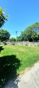 a field of green grass with a fence and trees at 8 mins drive to the airport in Christchurch