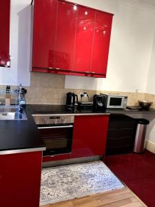 una cucina con armadi rossi e un piano cottura. di Flat in Central London a Londra