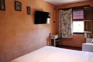 1 dormitorio con 1 cama y TV en la pared en Hotel Rural Carlos I en Garganta la Olla
