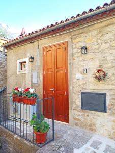 a building with a red door and flowers on a fence at Domus Al.Me in Castelmezzano