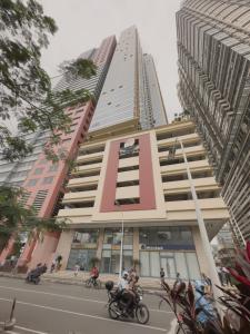 um edifício alto com pessoas a andar de mota à frente dele em SnugglePod Condotel - Grand Riviera Suites, US Embassy Manila, Roxas Blvd em Manila