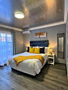 a bedroom with a large bed with yellow pillows at Luxury Garden Cottage in Welkom in Welkom