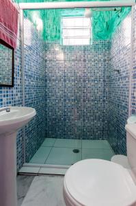 uma casa de banho com um chuveiro, um WC e um lavatório. em Pousada John John no Guarujá