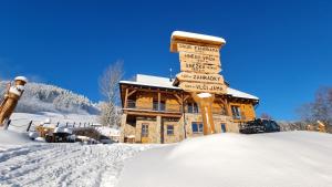 ein Schild im Schnee vor einer Lodge in der Unterkunft Penzion Srub Panorama in Pec pod Sněžkou