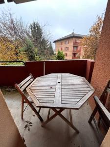 a wooden table and a chair on a balcony at Le Panoramique Gex in Gex