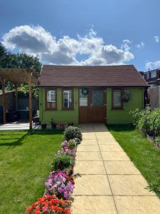una pequeña casa verde con flores en el patio en Charming Private Guest House en Enfield