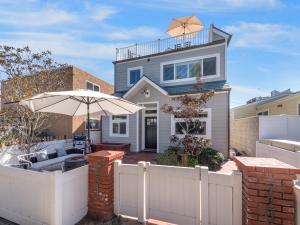 a house with a white fence and an umbrella at Kennebeck Oasis - Private Patio, Steps 2 Sand & AC in San Diego