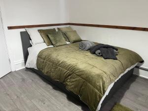 een bed met een groene deken en kussens erop bij Reservoir Retreat in Birmingham