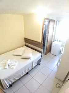 Schlafzimmer mit einem Bett mit weißer Bettwäsche und Kissen in der Unterkunft Hotel Praia e Sol in Matinhos
