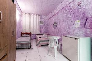 um quarto roxo com duas camas e uma mesa em Pousada John John no Guarujá