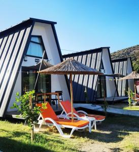 a house with two chairs and an umbrella at Adore Datca Beach House in Döşeme