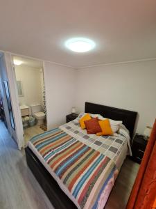 sypialnia z dużym łóżkiem z kolorowymi poduszkami w obiekcie ACOGEDOR Dpto FRENTE AL MAR EN EL TABO w mieście El Tabo