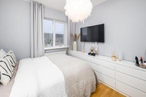 a white bedroom with a bed and a flat screen tv at Kopavogur Cozy Nest (3-bedrooms) in Reykjavík