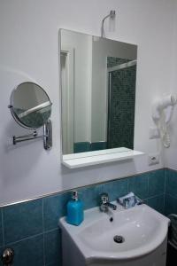 a bathroom with a white sink and a mirror at La Rosatea Rooms in Monreale