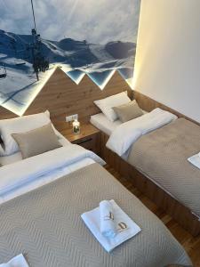 2 Betten mit Sandalen und Handtüchern auf einem Zimmer in der Unterkunft Dream Luxury Jahorina in Jahorina