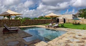 a pool with two chairs and two umbrellas at 4 U Luxury Bungalows Diani in Diani Beach