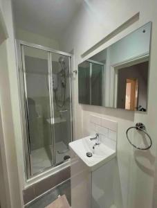 baño blanco con ducha y lavamanos en New modern studio flat, en Brighton & Hove