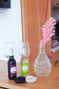 twee flessen wijn en een vaas met bloemen op een tafel bij Kleine studio op boerenerf vlakbij Amsterdam. in Uitgeest