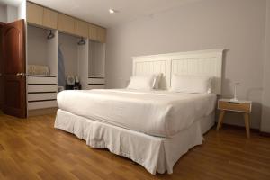 a bedroom with a large bed with white sheets and pillows at Santa Lucia Suites - Barranco in Cuenca
