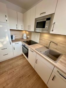 eine Küche mit weißen Schränken, einer Spüle und einer Mikrowelle in der Unterkunft Ferienwohnung Bad Sachsa Harz II in Bad Sachsa