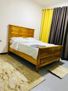 a bedroom with a wooden bed and a yellow curtain at Drew Apartment Tanga in Tanga